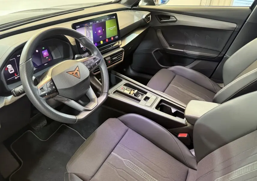 Intérieur du CUPRA Formentor noir 2023, vue côté conducteur, volant cuir, écran tactile central et sièges tissu gris.