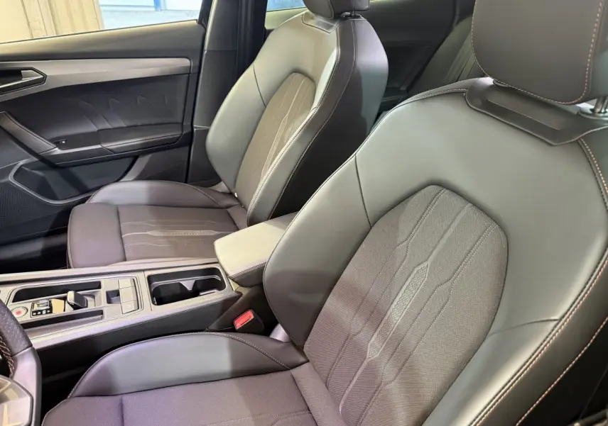 Gros plan sur les sièges avant en cuir et tissu gris du CUPRA Formentor avec surpiqûres orange visibles côté conducteur.