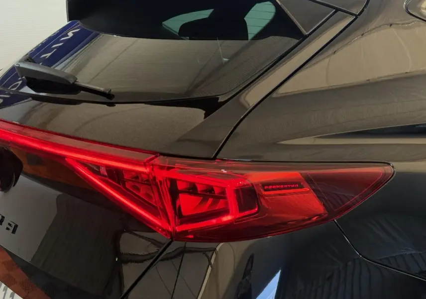 Gros plan sur le feu arrière droit rouge du CUPRA Formentor noir 2023, mettant en valeur le logo et la carrosserie brillante.