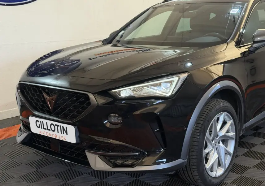 Vue 3/4 avant droit d'un CUPRA Formentor noir brillant avec calandre noire et jantes argentées en exposition intérieure.