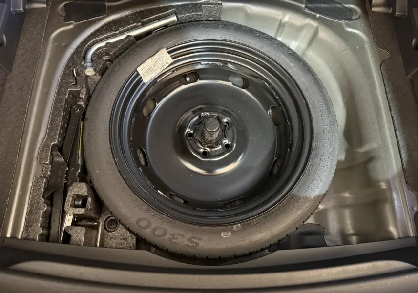Gros plan sur la roue de secours galette noire dans le coffre du CUPRA Formentor 1.5 TSI 2023 noir.