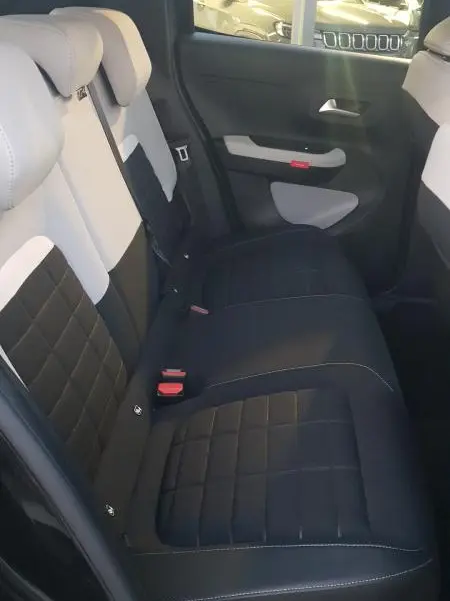Vue intérieure arrière droite des sièges bicolores noir et blanc de la Citroën C3 Turbo 100 ch 2025 avec habillage de porte assorti.