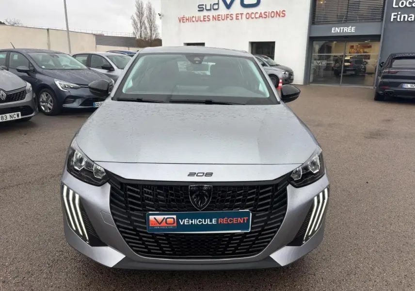 Vue avant d'une Peugeot 208 Hybrid gris métallisé avec calandre noire et feux diurnes LED en forme de griffes.