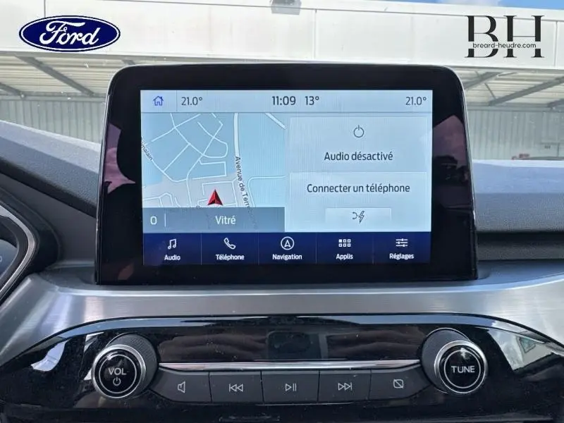 Écran tactile central du Ford Kuga 2023 affichant la navigation et les commandes multimédias, intérieur gris.