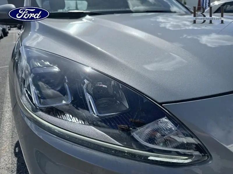 Gros plan sur le phare avant gauche du Ford Kuga 2023 gris Solar métallisé, mettant en valeur ses lignes modernes et LED.