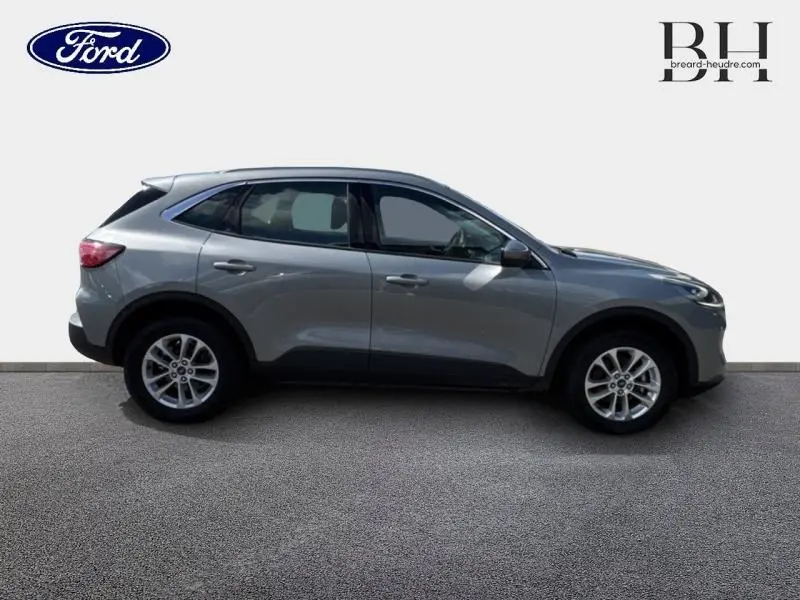 Vue latérale droite du Ford Kuga 2023 gris Solar Métallisé avec jantes alu et barres de toit visibles.