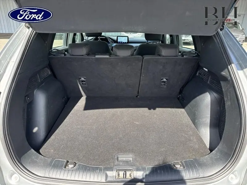 Coffre ouvert du Ford Kuga gris Solar Métallisé, vue arrière montrant l’espace de chargement et la banquette arrière.