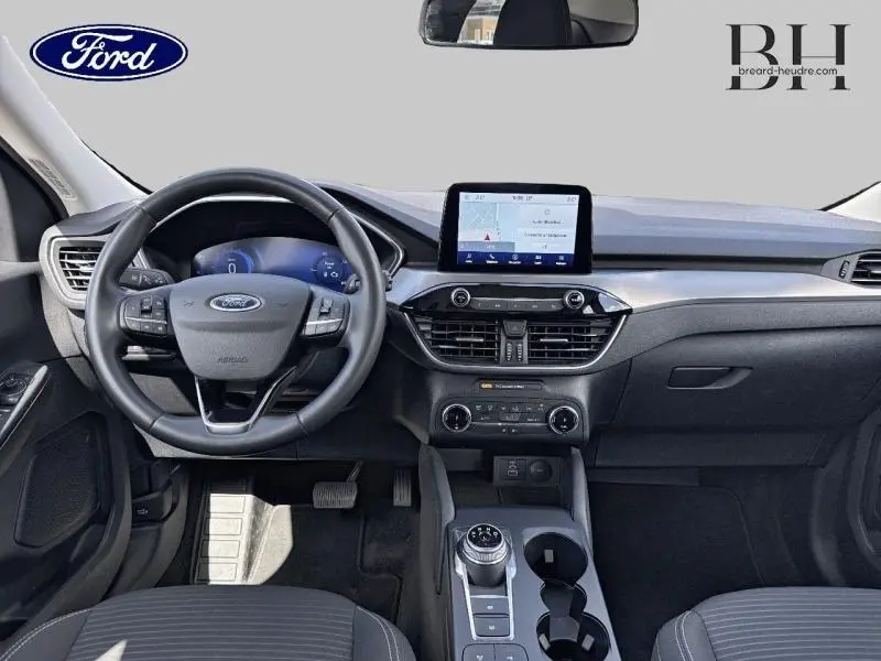 Vue intérieure avant du Ford Kuga 2023 avec tableau de bord moderne, écran tactile central et volant cuir multifonction.