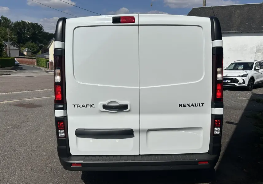 Vue arrière d’un Renault Trafic blanc avec portes battantes fermées et feux arrière verticaux visibles.