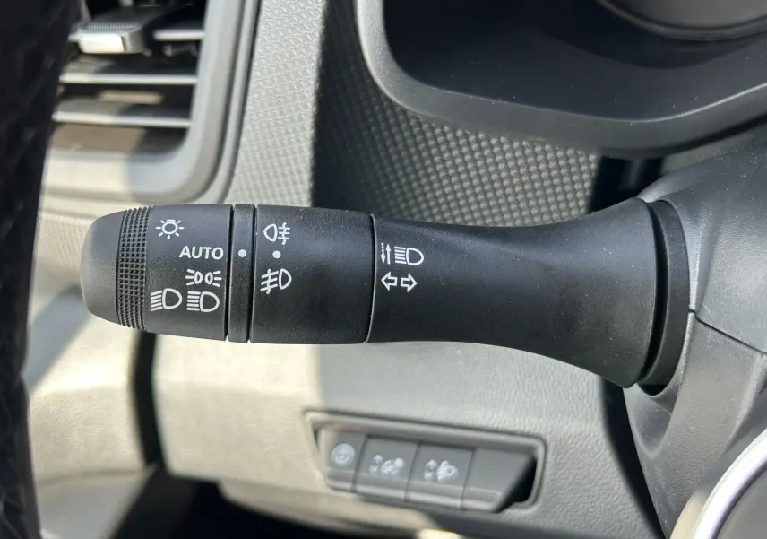 Gros plan sur la commande des feux et clignotants dans l’habitacle du Renault Trafic blanc, côté gauche du volant.
