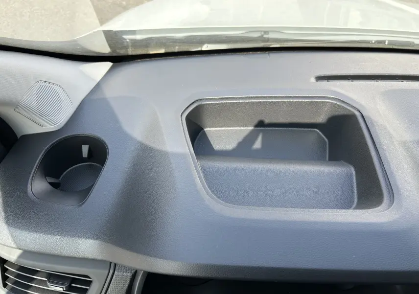 Détail intérieur du tableau de bord noir du Renault Trafic cabine approfondie, avec rangement intégré et porte-gobelet.