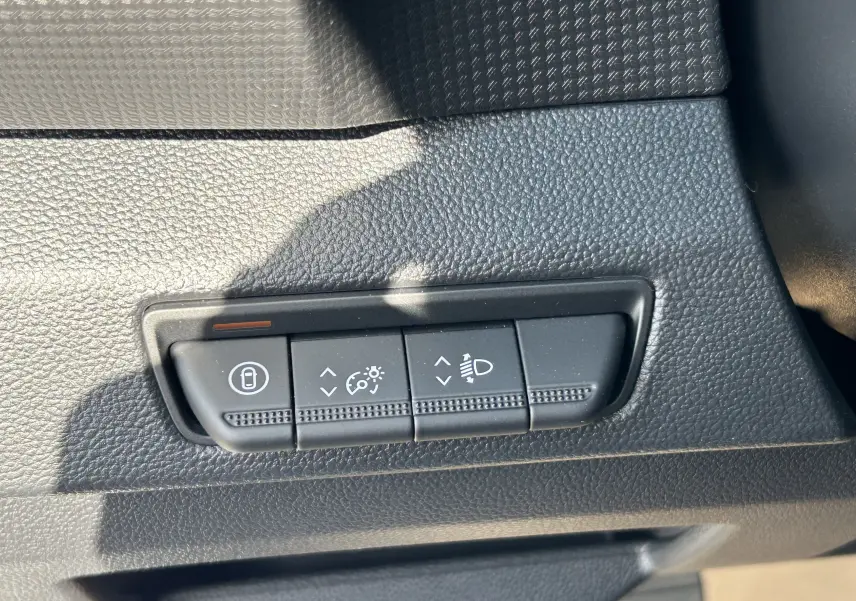 Gros plan sur les commandes de réglage d’éclairage et verrouillage dans l’habitacle noir du Renault Trafic blanc.