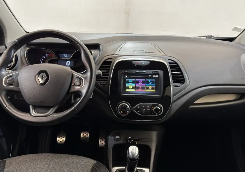 Vue intérieure avant du tableau de bord noir du Renault Captur Intens TCe 90 avec volant cuir multifonctions et écran tactile central.