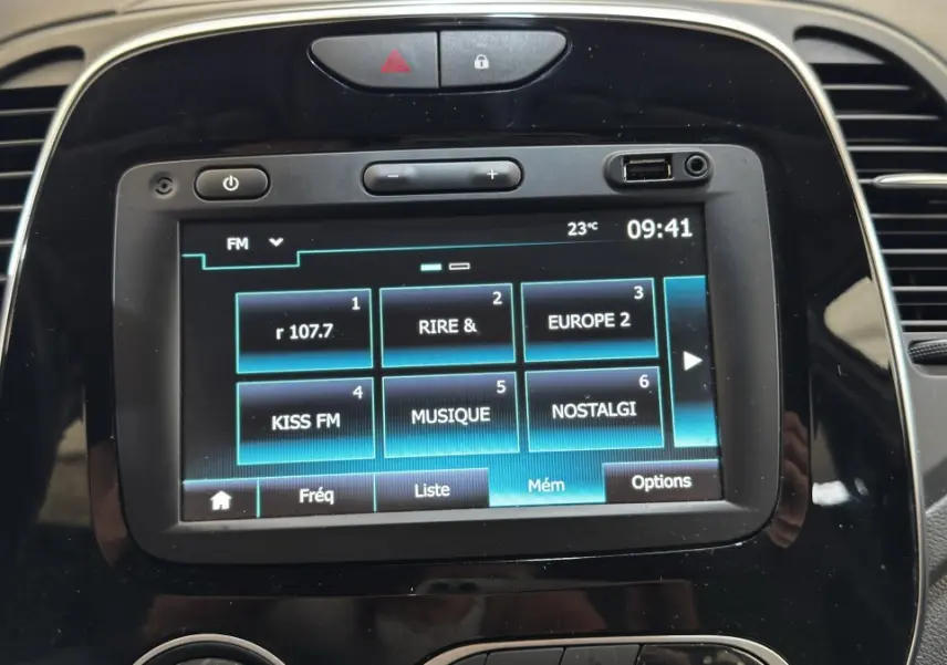 Vue rapprochée de l'écran tactile central noir du tableau de bord du Renault Captur blanc, affichant les stations radio FM.