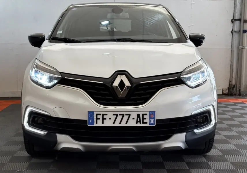 Vue avant d'un Renault Captur Intens TCe 90 blanc avec phares LED allumés et calandre noire distinctive.