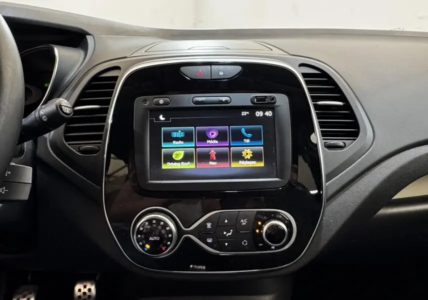 Vue intérieure centrée sur la console tactile noire du Renault Captur blanc 2019 avec commandes climatisation et volant partiel.