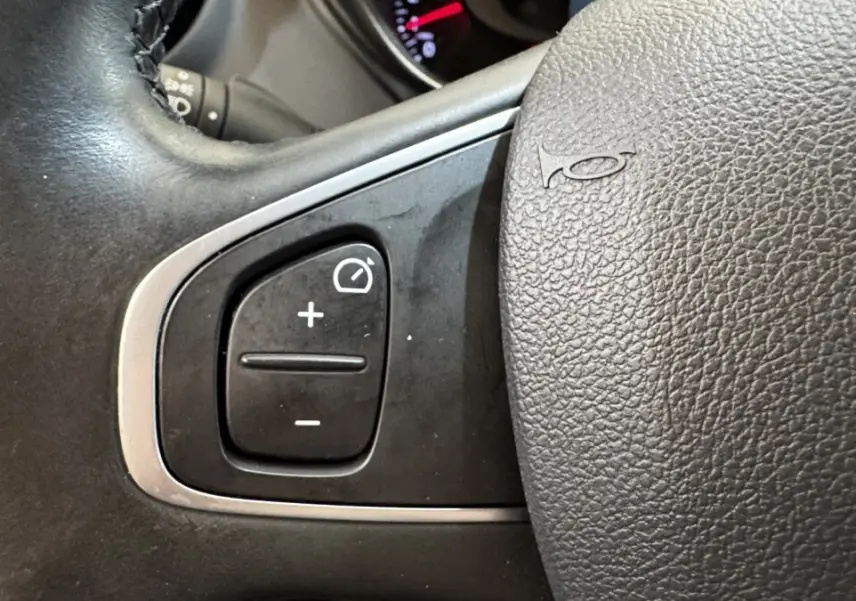 Gros plan sur le volant cuir noir du Renault Captur Intens TCe 90, avec commandes de régulateur de vitesse.