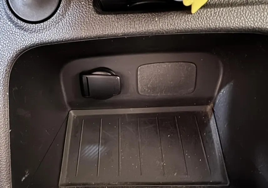 Gros plan sur la prise 12V noire dans le compartiment de rangement intérieur du Renault Captur blanc Intens TCe 90.