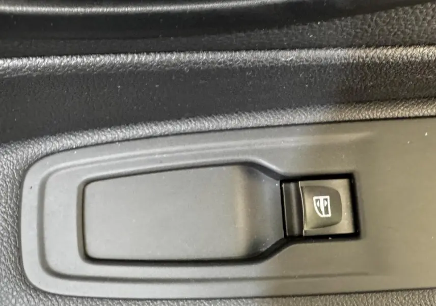 Gros plan sur le bouton de commande électrique de la vitre côté conducteur du Renault Captur blanc Intens TCe 90 2019.