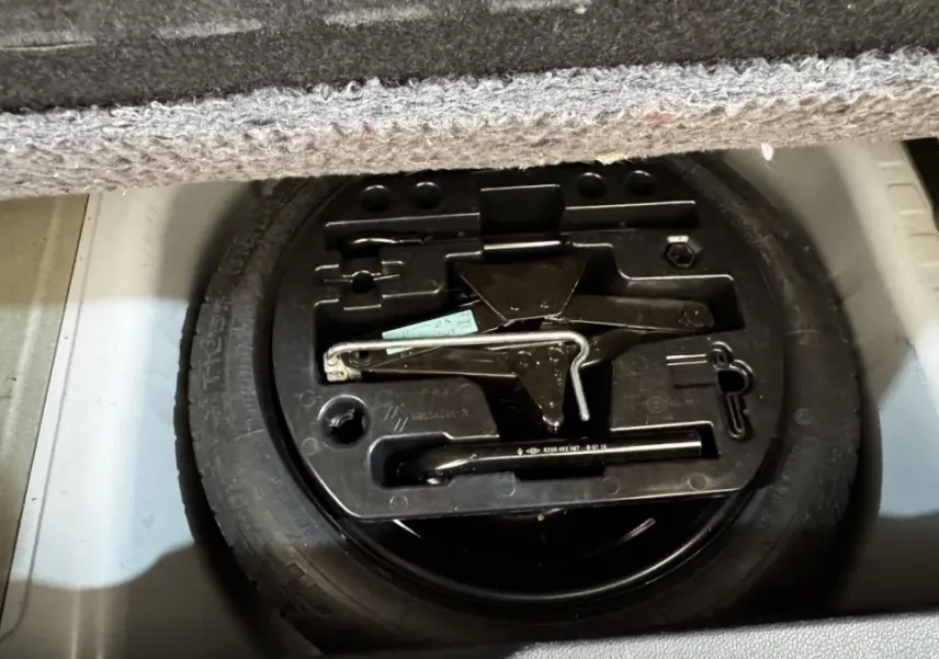 Vue rapprochée du coffre du Renault Captur blanc 2019 montrant la roue de secours et les outils de changement de pneu.
