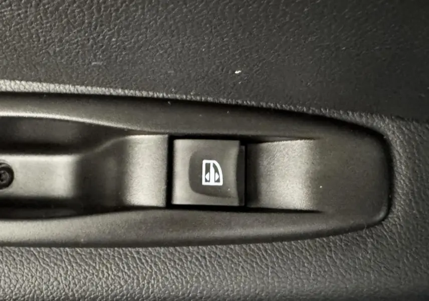 Gros plan sur l'interrupteur de lève-vitre noir dans l'habitacle d'un Renault Captur blanc Intens TCe 90.