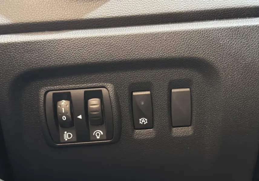 Gros plan sur les commandes de réglage des phares et du tableau de bord du Renault Captur Intens TCe 90 2019.