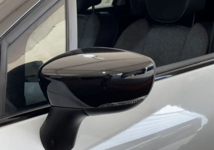 Rétroviseur noir en gros plan côté gauche d’un Renault Captur blanc, avec reflet et partie de la portière visible.