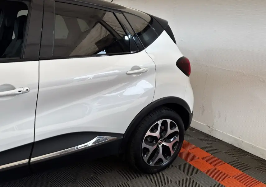 Vue côté arrière droit du Renault Captur blanc 2019 avec toit noir et jantes alliage distinctives.