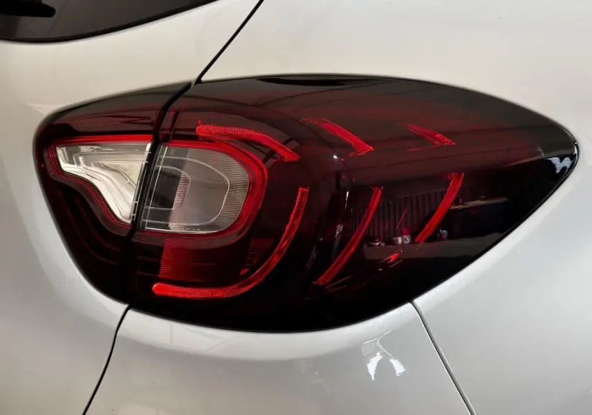 Gros plan sur le feu arrière droit rouge fumé du Renault Captur blanc, version Intens TCe 90 de 2019.