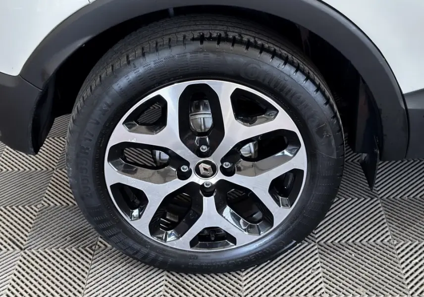 Gros plan sur la roue avant droite du Renault Captur blanc, mettant en valeur la jante alliage bicolore au design moderne.
