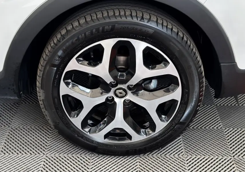 Gros plan sur la roue avant droite du Renault Captur blanc, avec jante alliage bicolore et logo Renault central.