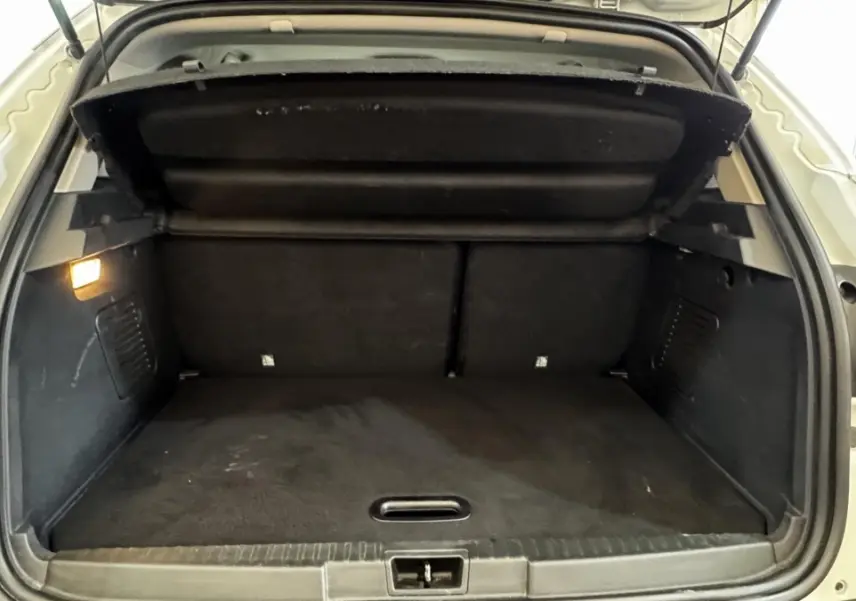 Coffre ouvert vu de l'arrière d'un Renault Captur blanc 2019, avec intérieur de coffre noir et éclairage latéral.