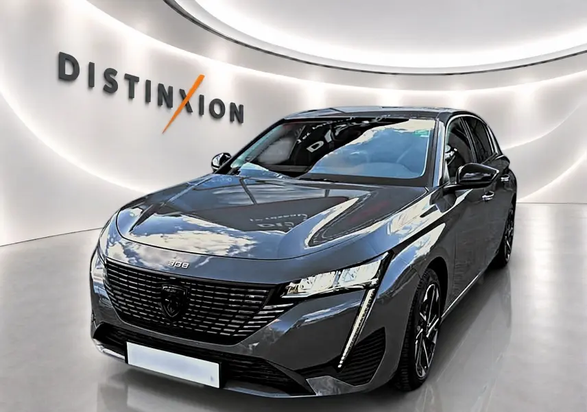 Peugeot 308 gris selenium vue 3/4 avant droit avec calandre noire et feux LED verticaux allumés.