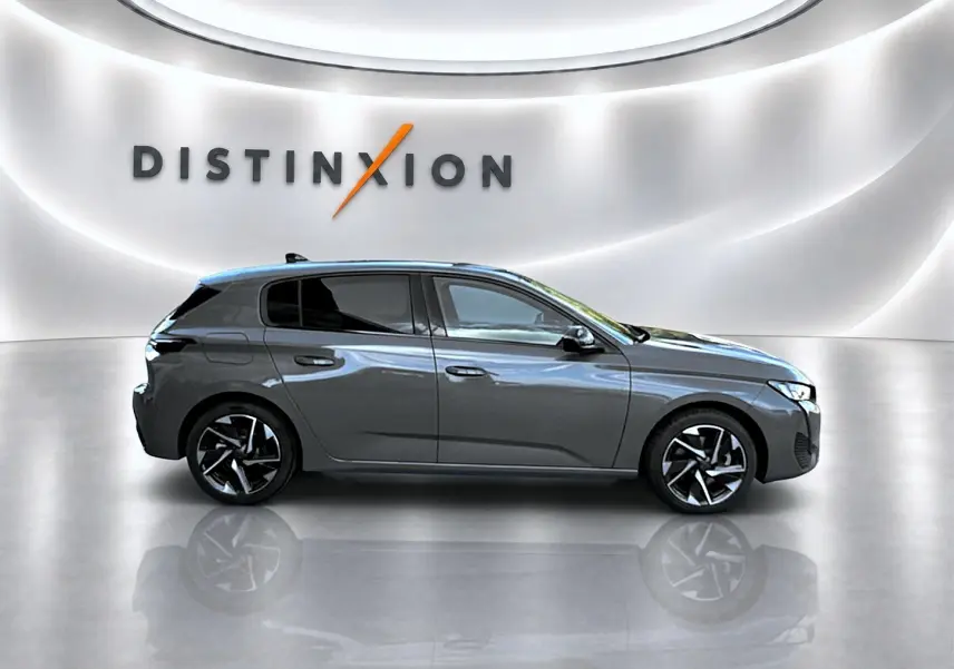Profil droit d'une Peugeot 308 gris selenium 2025 dans un showroom avec jantes alliage et vitres surteintées.