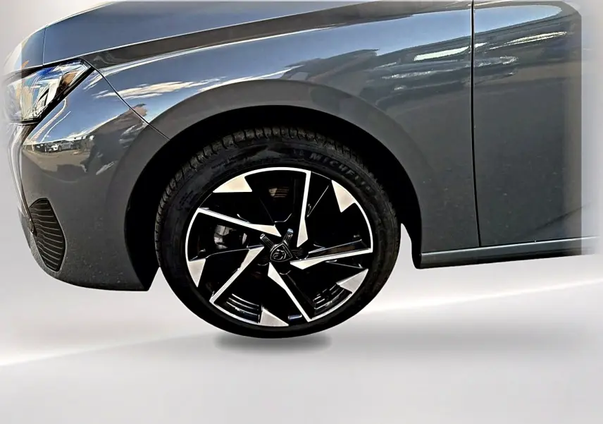 Gros plan sur la roue avant gauche et l'aile d'une Peugeot 308 gris selenium avec jante alu noire et argent.