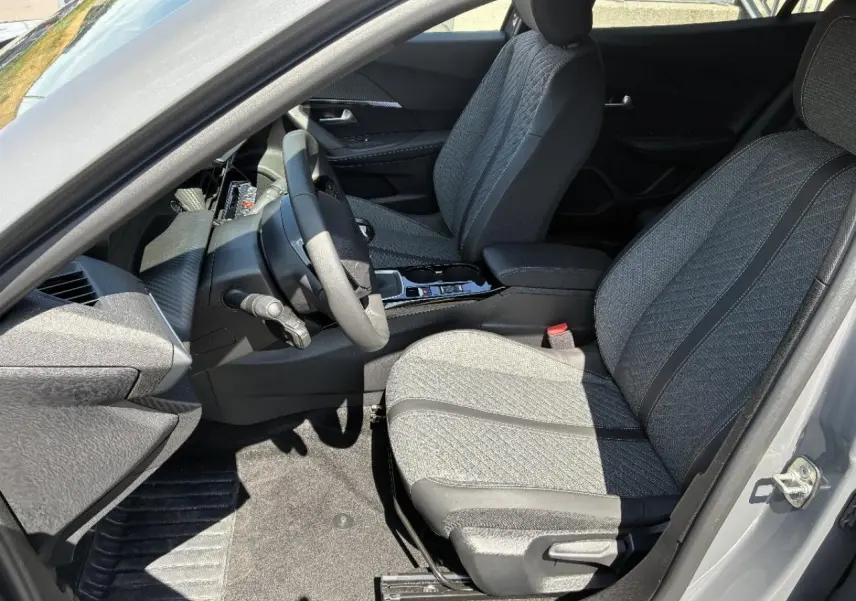 Vue intérieure côté conducteur du Peugeot 2008 2024 sellenium, montrant les sièges tissu gris et la console centrale.