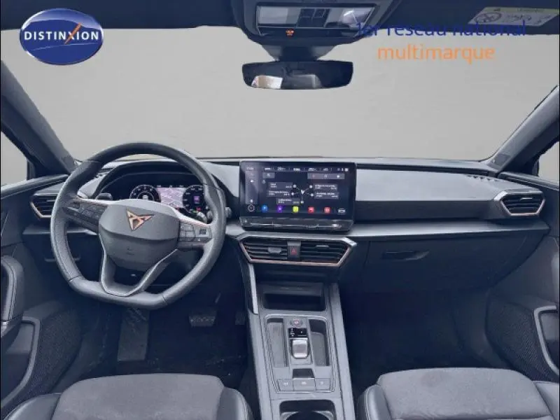 Intérieur avant de la CUPRA Leon 2024 avec tableau de bord moderne et écran tactile central, volant cuir multifonction.