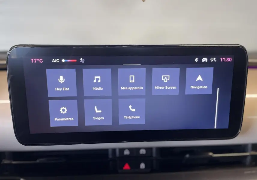 Écran tactile central affichant le système Uconnect dans un Fiat 600 beige métallisé, planche de bord claire visible en arrière-plan.