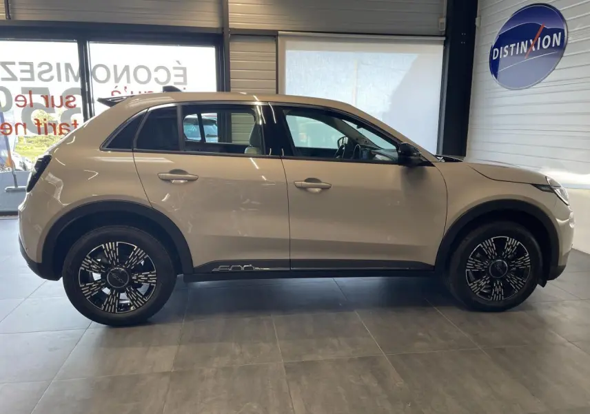 Profil latéral droit d'une FIAT 600 beige métallisé avec jantes alliage noires et logo 600 sur la bas de caisse.