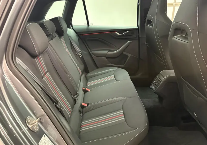 Vue intérieure arrière côté gauche du Skoda Kamiq Monte Carlo 2024 avec sièges tissu gris à bandes rouges et grises.