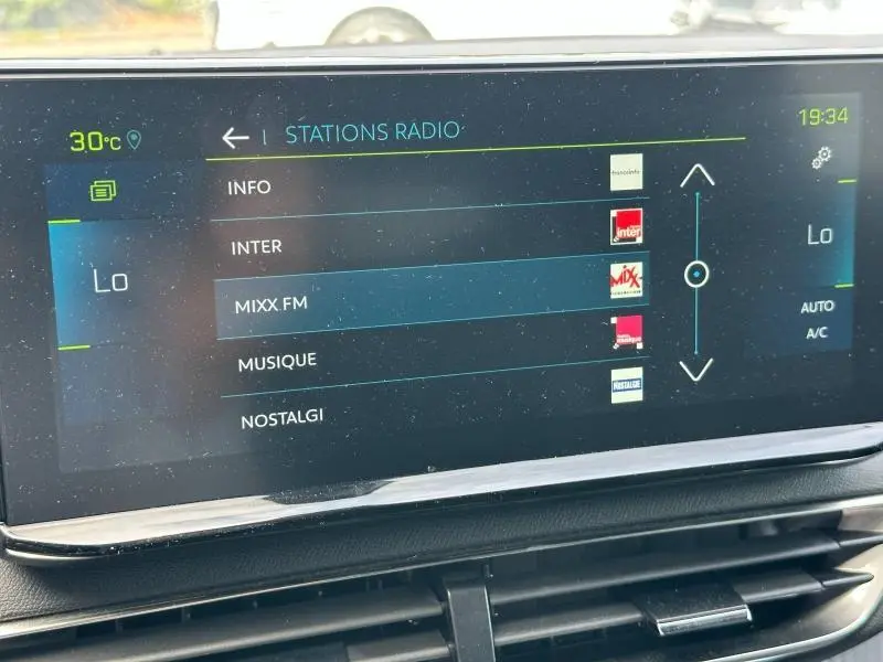 Écran tactile central du Peugeot 3008 Hybride bleu, affichant la sélection des stations radio en intérieur.