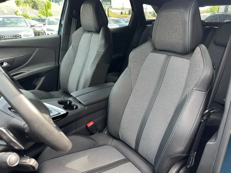 Vue intérieure côté conducteur du Peugeot 3008 hybride rechargeable 2024, sièges tissu gris et cuir noir avec surpiqûres.