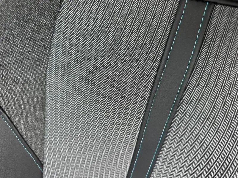 Détail du tissu gris à chevrons et surpiqûres bleues sur le siège arrière du Peugeot 3008 Hybride 2024.