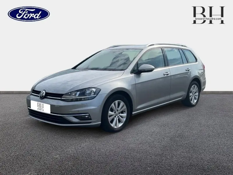 Volkswagen Golf SW gris Tungsten vue 3/4 avant droit, avec jantes alu et barres de toit visibles.