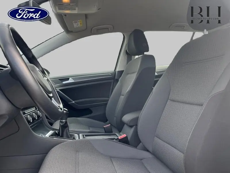 Vue intérieure côté gauche de la Volkswagen Golf SW gris Tungsten, montrant les sièges avant et le volant cuir multifonction.