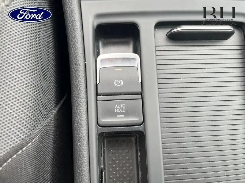 Gros plan sur la console centrale noire avec frein à main électrique et bouton Auto Hold d'une Volkswagen Golf SW gris Tungsten.