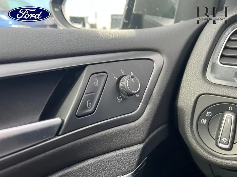 Vue rapprochée sur les commandes de réglage des rétroviseurs et des feux côté gauche intérieur d'une Volkswagen Golf SW gris Tungsten.