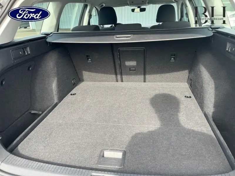 Vue intérieure du coffre spacieux et tapis gris d'une Volkswagen Golf SW 2019, avec banquette arrière rabattue et cache-bagages.