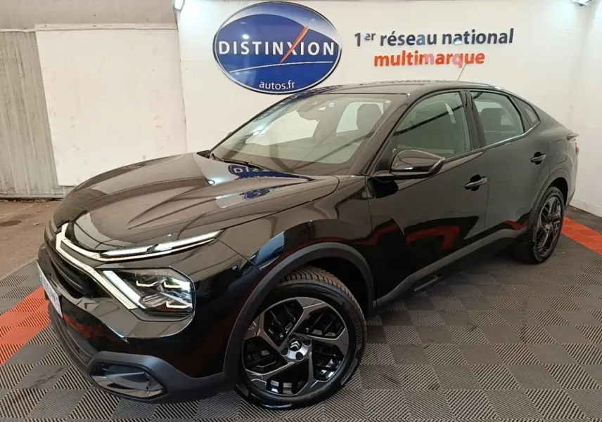 Citroën C4 X noir vue 3/4 avant droit, avec jantes noires et phares LED ellipsoïdaux visibles en intérieur showroom.