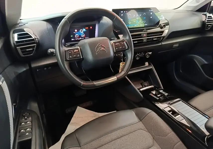 Vue intérieure du poste de conduite de la Citroën C4 X noire, avec volant cuir multifonctions et écran tactile central.